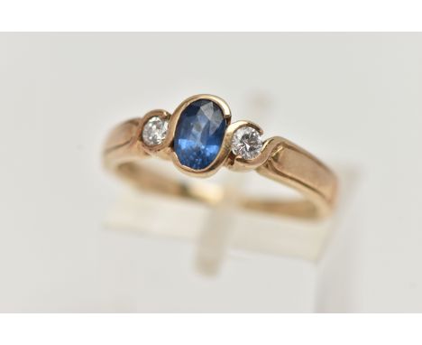 A 9CT GOLD SAPPIRE AND DIAMOND RING, designed with a central oval cut blue sapphire, collet set, flanked with round brilliant