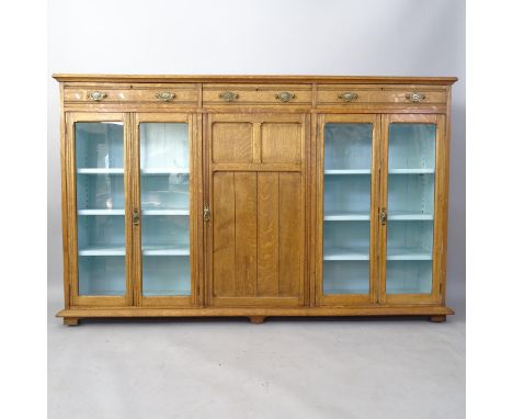 A large late Victorian oak bookcase, with 3 frieze drawers, glazed and panelled cupboards under, 195cm x 123cm x 34cm (with k