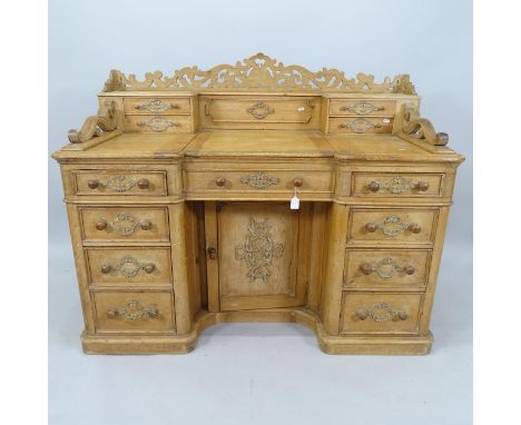 An Antique pine kneehole desk with raised back, lifting top revealing well fitted interior, and 9 drawers, with cupboard unde