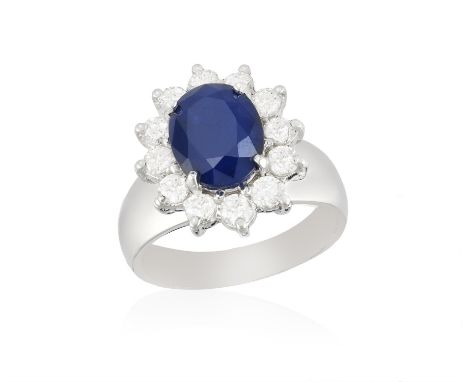A SAPPHIRE AND DIAMOND CLUSTER RING, the oval-shaped sapphire weighing approx. 3.00cts, within a surround of brilliant-cut di