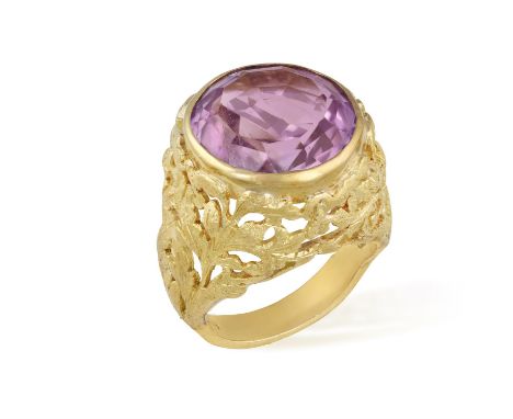 AN AMETHYST RING, set with a circular amethyst at the centre within collet-setting, to a textured gold openwork gallery with 