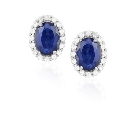 A PAIR OF SAPPHIRE AND DIAMOND CLUSTER EARSTUDS, each oval-shaped sapphire within a brilliant-cut diamond frame, mounted in 1