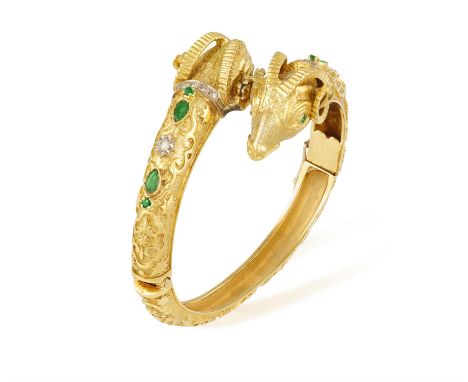 AN EMERALD AND DIAMOND BANGLE, the hinged bangle composed of two ram's head highlighted with various cuts of emeralds and dia