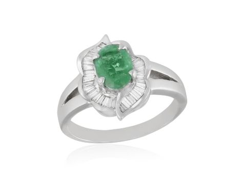 AN EMERALD AND DIAMOND CLUSTER RING, the oval-shaped emerald set within a tapered baguette-cut diamond surround, mounted in 1