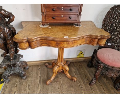 A Victorian walnut pedestal card table, serpentine top with brown baize and tooled leather interior, recessed counter wells a