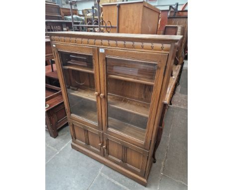 An Ercol elm bookcase, bevelled glass to the doors. 