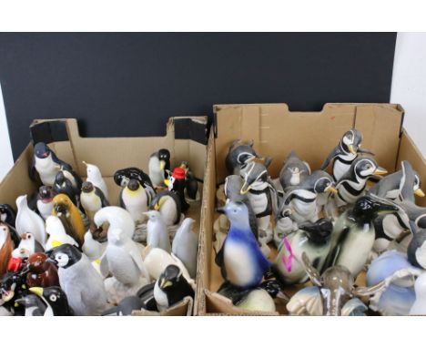 A large collection of ceramic and resin penguin ornaments contained within two boxes. 