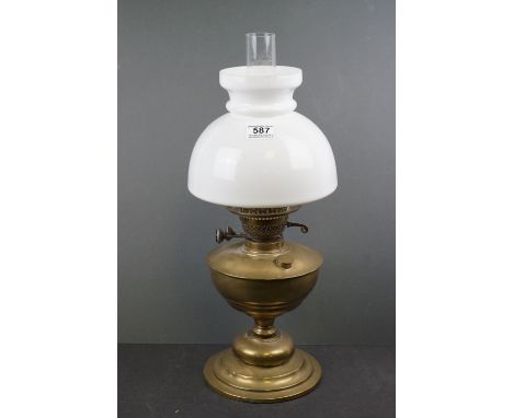A brass oil lamp with white glass shade. 