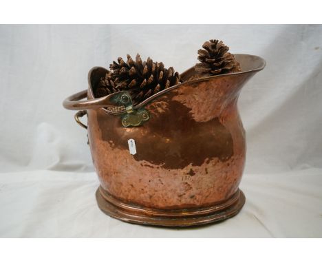 An antique helmet copper coal bucket together with a table lamp. 