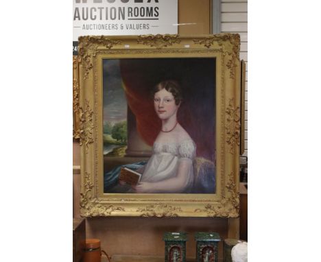 A large early 19th century oil on canvas painting mounted in an ornate gilt portrait of a young women holding a book seated i