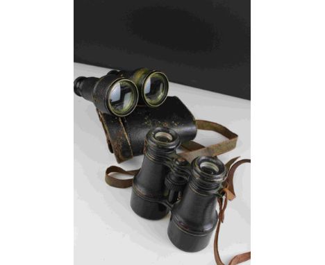 A pair of world war one era British military issued field binoculars, marked with the broad arrow and complete with leather c