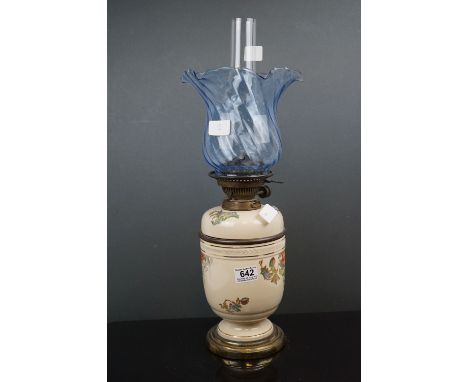 A 20th century porcelain oil lamp with floral decoration and blue twisted scallop topped shade. 