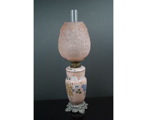 A pink ground ceramic oil lamp decorated with butterflies and fauna, mounted on a metal base, of rococo style, with pink flor