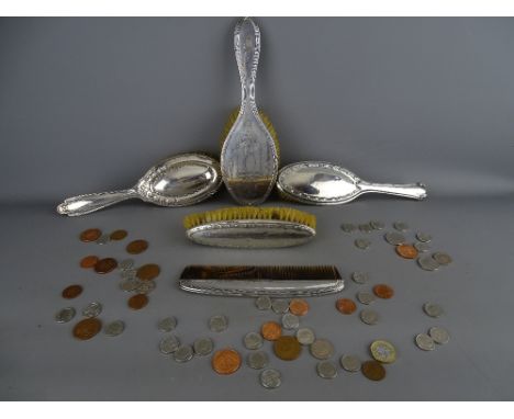 Four various silver backed dressing table brushes and a comb with a quantity of current coinage