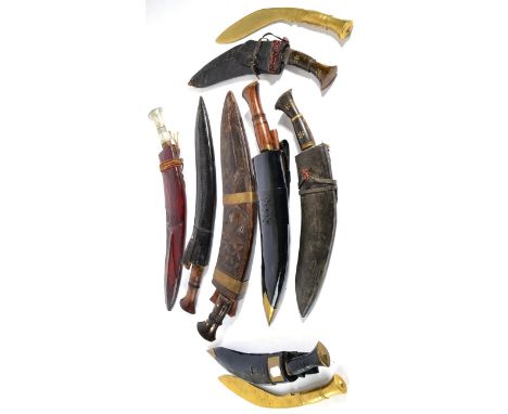 Seven Various Native Kukris, one with large foliate carved wood two piece scabbard, one with white metal hilt and leather sca