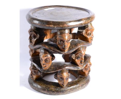 A Bamileke (Cameroon), Anthropomorphic Stool, carved from a single trunk of wood, the circular seat with rolled edge, support