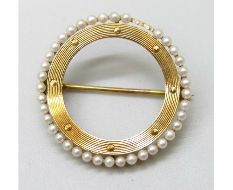 A 14ct gold circular brooch with seed pearl border, lacking two pearls and misshapen, 2.5g, 2.2cm