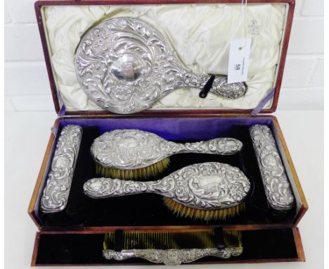 An Edwardian silver backed dressing table set, contained within a tan leather case, comprising hand mirror, two hair brushes,