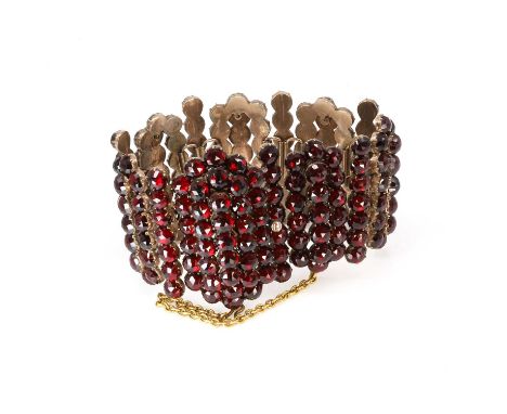 A Bohemian garnet cuff bracelet, with elongated domed panels interspaced with bars, clawed collet set throughout with faceted