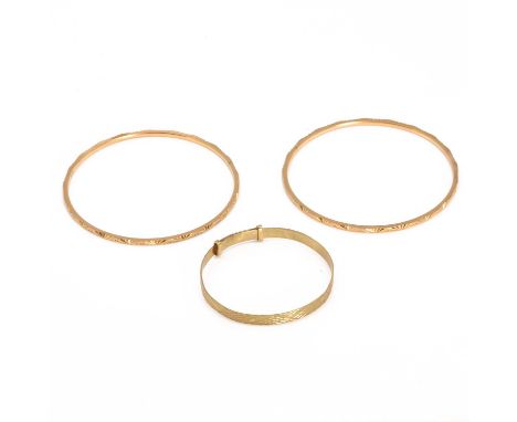 A group of three gold bangles, a 9ct gold engraved baby bangle, London 1967, and a pair of engraved bangles, both tested as a