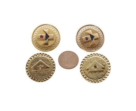 A group of four badges, two 9ct gold badges,each with a central round cut gemstone and a faceted machine engraved border, 25m