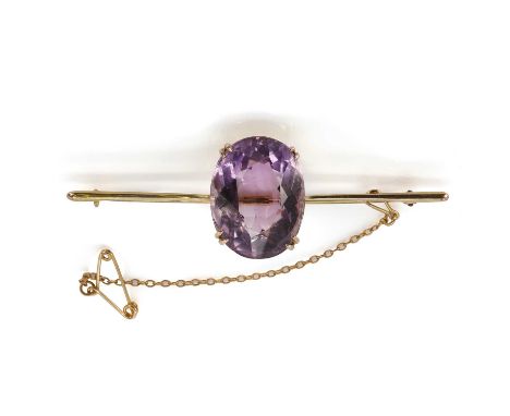 A gold amethyst set bar brooch, with an oval cut amethyst, 16mm x 21mm, set with four double claws to a plain tapered bar, to