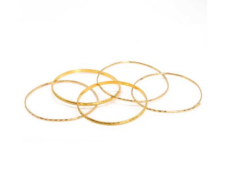 A group of five gold bangles, two 18ct gold solid bangles, round in shape with foliate engraving and a D profile, internal di