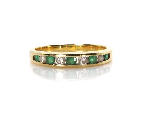 An 18ct gold emerald and diamond half eternity ring,  with graduated round brilliant cut diamonds alternating to circular cut