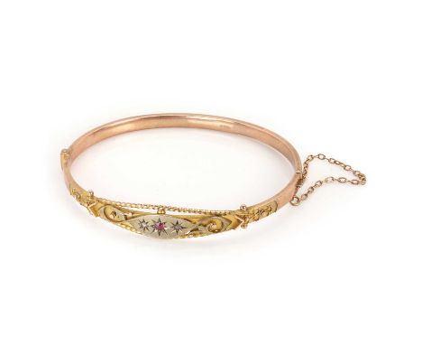 An Edwardian 9ct gold ruby and rose cut diamond bangle, with a central round cut ruby, flanked by a rose cut diamond to eithe