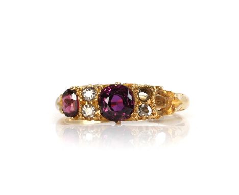 A Victorian 18ct gold carved head ring,  of three-stone design, with a central round mixed-cut ruby flanked by pairs of old s