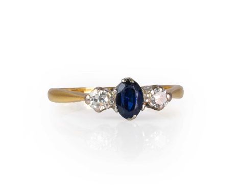 A sapphire and diamond three stone ring,  with an oval cut sapphire flanked by two round brilliant cut diamonds, to tapered s