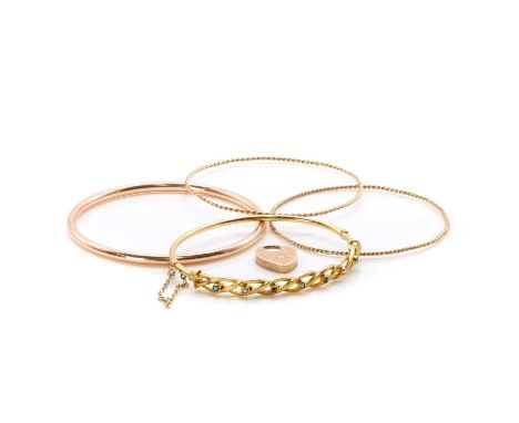 A group of four bangles, a 9ct gold bangle, round in shape with a round wire profile, internal diameter 64mm, hallmarked Ches