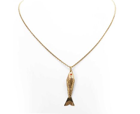 An articulated fish pendant, the pendant with round red glass eyes, bezel set, with engraved detail to the articulated sectio