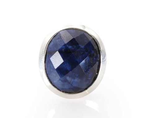 A silver and sapphire single stone ring,  with an oval chequerboard cut sapphire, 19mm x 17mm, bezel set into a wide D sectio