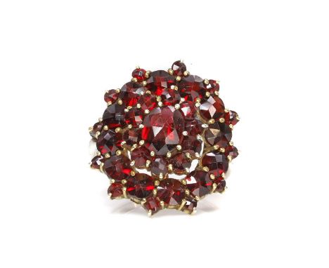 A garnet cluster ring,  with a central oval checkerboard cut garnet, to a surround of round rose cut garnets, all claw set to