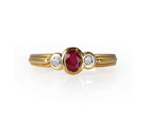 An 18ct gold ruby and diamond ring,  with a central oval cut ruby, flanked by round brilliant cut diamonds, all bezel set, to