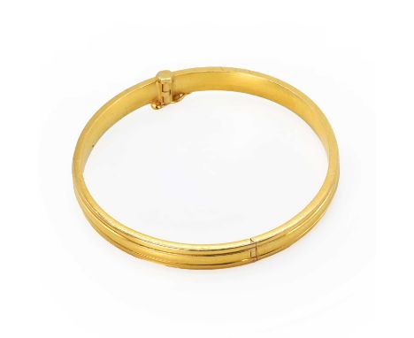 A gold hinged bangle, a hollow bangle encircled by two incised lines, to a screw clasp and single figure of eight safety catc