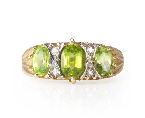 A peridot and diamond three stone ring,  with graduated oval cut peridot, the central peridot flanked by round brilliant cut 