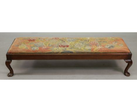 A reproduction early 18th century style narrow rectangular mahogany fender stool, with floral needlework seat, on cabriole le