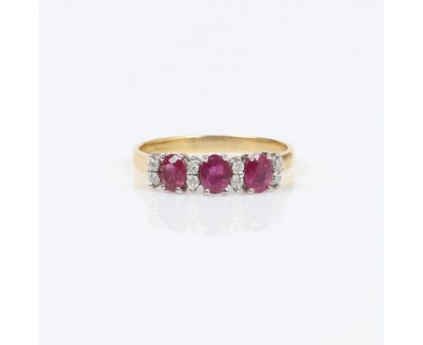 18CT GOLD RUBY AND DIAMOND DRESS RING. Set with three oval faceted rubies, each measuring approx. 5 x 4mm. Also set with eigh