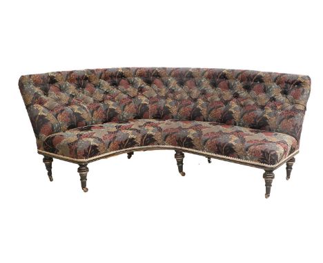 A Victorian Ebonised and Parcel-Gilt Curved Sofa, late 19th century, recovered in blue and red floral fabric with buttoned ba