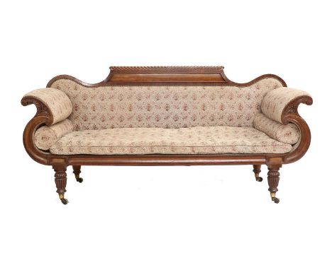 A Regency Carved Mahogany Scroll-End Sofa, early 19th century, covered in close-nailed floral beige fabric, the gadrooned top