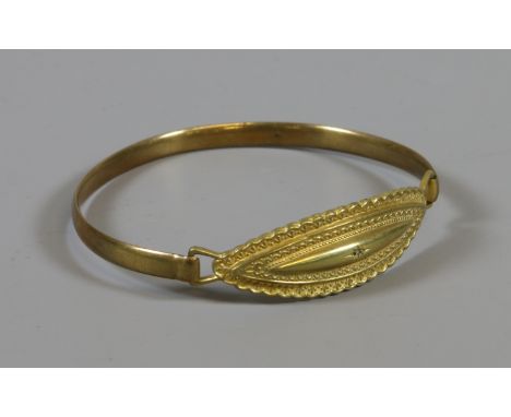 A rolled gold bangle set with a single diamond.