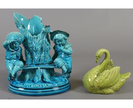 A small Burmantofts olive glazed posy in the form of a swan and a Burmantofts spill vase formed as a tree trunk surmounted wi