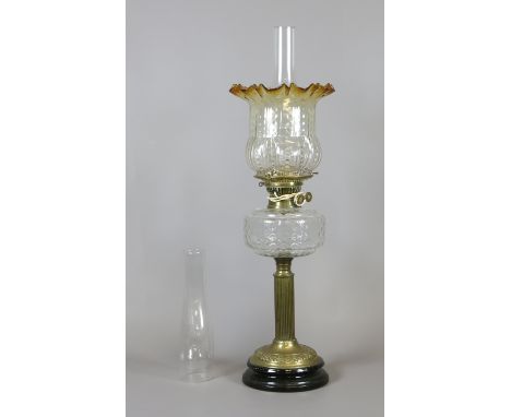 A Victorian oil lamp converted with moulded amber tint shade, clear glass font and raised over a reeded brass column