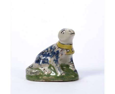 Delftware model of a dog 18th Century, blue and manganese sponged decoration and green mound base, 5.5cm high x 6cm across