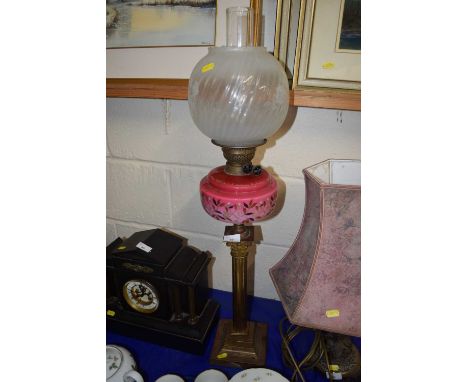 An oil lamp with opaque glass shade, pink glass font and brass base