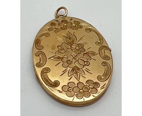 A large vintage oval shaped 9ct gold locket with front floral decoration and engine turned pattern to back. Bale marked 375. 