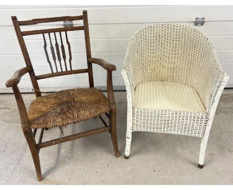 A vintage wooden rush seated low armchair with shaped spindle style back (seat a/f). Together with a painted white Lloyd Loom