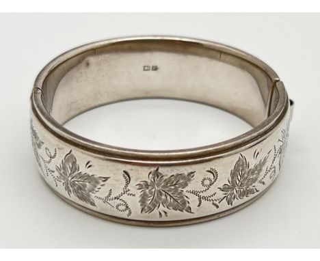 A vintage silver bangle with leaf engraved decoration. Extending hook and eye clasp. Inside of bangle hallmarked for Birmingh
